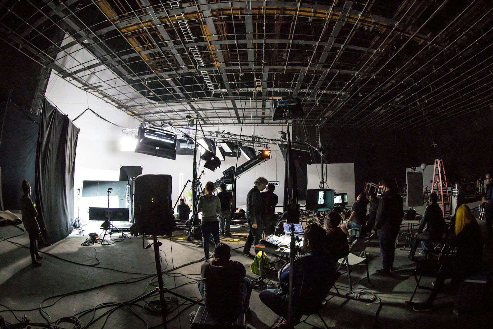 Film crew on a large soundstage under a lighting grid